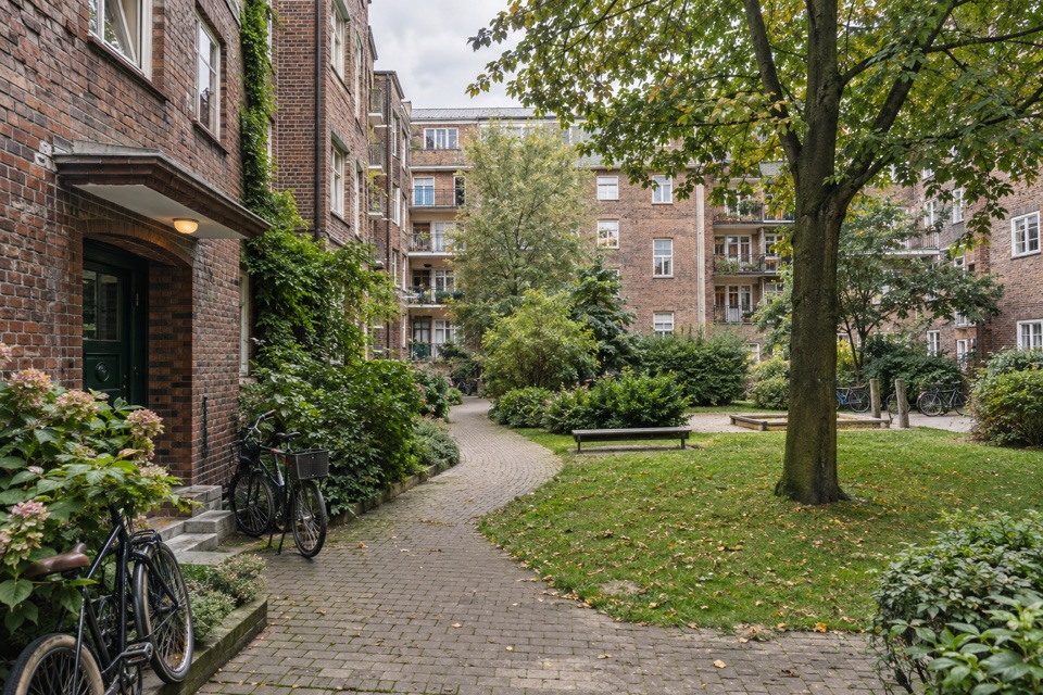 Grüner Innenhof zwischen Hamburger Mietshäusern als Wohnbeispiel